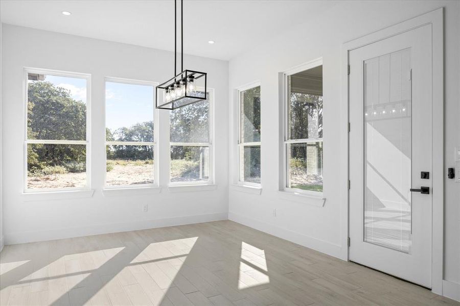 Open-concept Dining room featuring Porcelain Tile-finish flooring, recessed lighting, and a contemporary black metal chandelier. Also showing the door to the backyard patio.