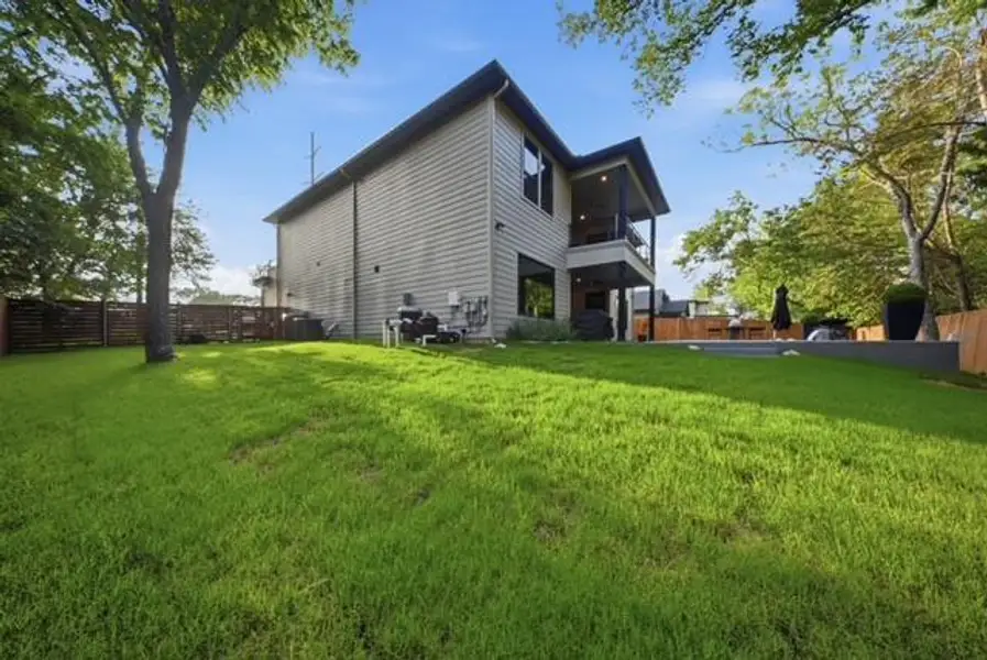 Spacious backyard featuring a lush lawn, privacy fencing, a multi-level deck, and an integrated outdoor entertainment area