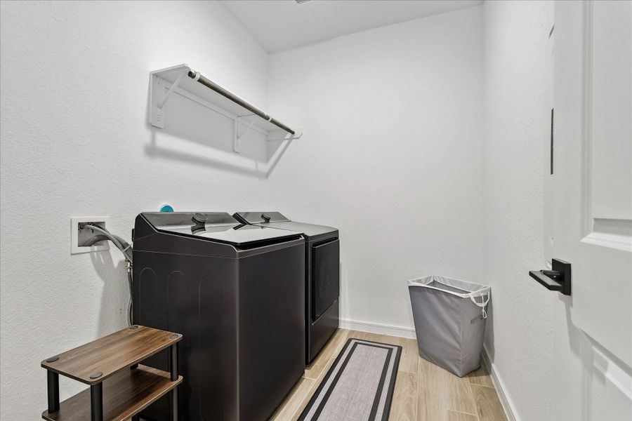 Large interior utility room with full-size washer and dryer space, additional storage potential, and convenient access from the primary suite.