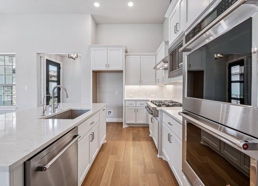 Kitchen featuring appliances with stainless steel finishes, light wood-style flooring, recessed lighting, white cabinetry, and backsplash