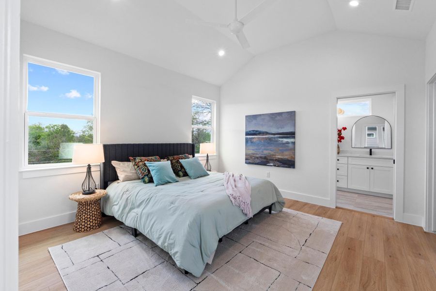 High vaulted ceilings and rich wood floors anchor this serene primary bedroom suite.