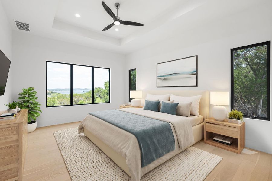 Virtually staged primary bedroom retreat features a tray ceiling, recessed lighting, and a panoramic lake view from generous windows.