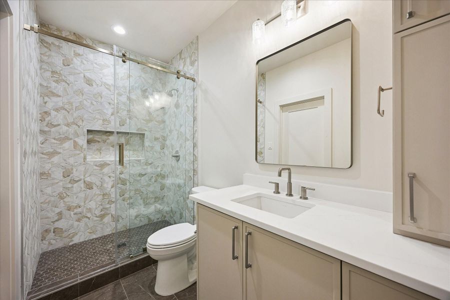 Overnight guests will appreciate the privacy of their own ensuite, complete with a glass enclosed walk-in shower, a sleek vanity with ample storage and polished finishes that carry the home’s custom feel throughout.