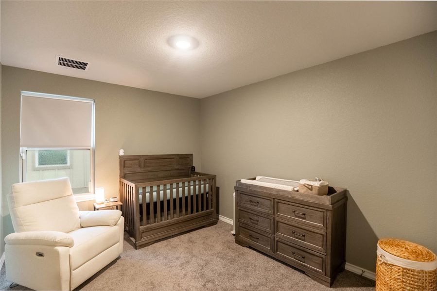 Bedroom with a crib, light colored carpet, and a textured ceiling Bedroom with a crib, light colored carpet, and a textured ceiling