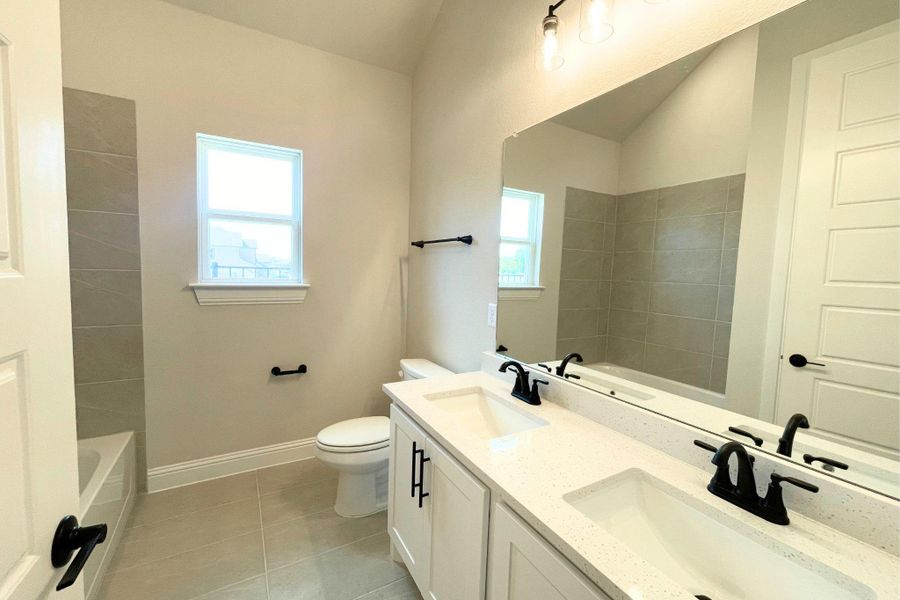 High vaulted ceilings and a double vanity define this modern, stone-countered bathroom design. High vaulted ceilings and a double vanity define this modern, stone-countered bathroom design.