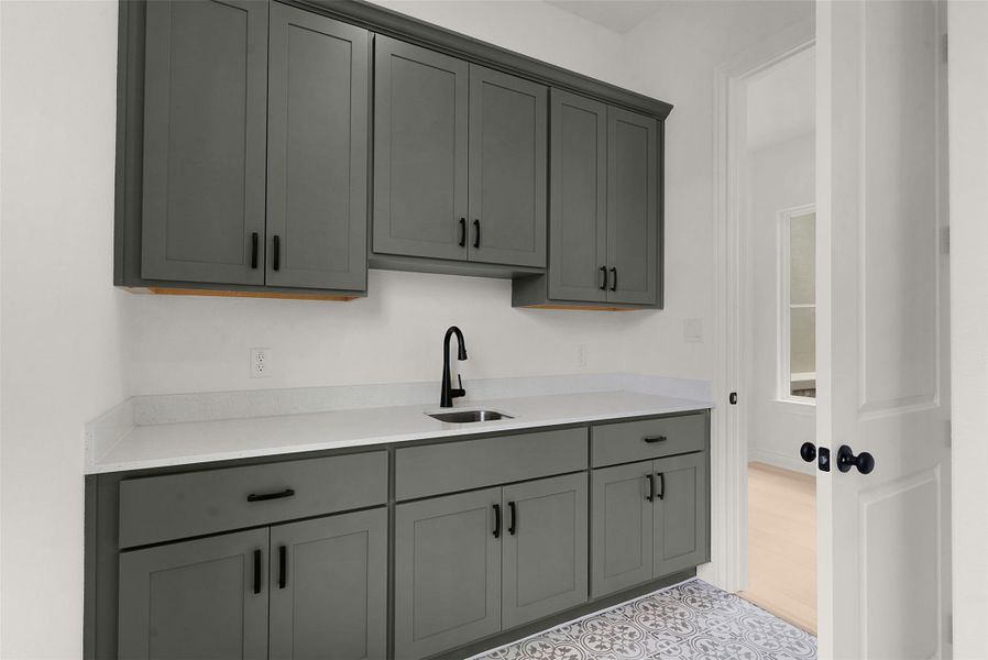 A well-appointed utility room features abundant cabinetry and durable countertops, creating a functional and organized space.