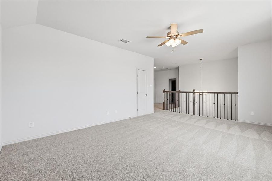 Carpeted spare room featuring ceiling fan and baseboards