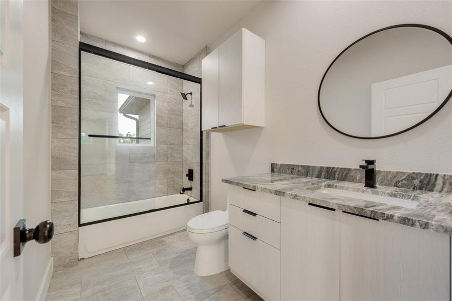 Full bathroom with vanity, combined bath / shower with glass door, and toilet