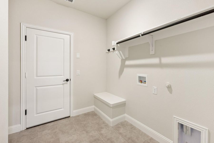 Laundry room with wall-mounted clothing rod, built-in bench, washer hookups, and tile floors