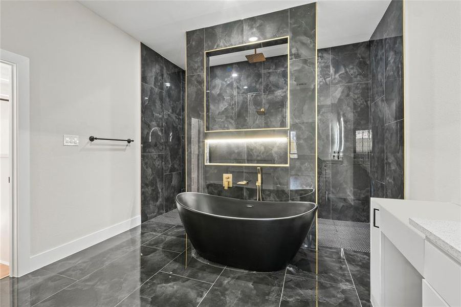 Full bath featuring dark marble finish flooring, a freestanding bath, and a marble finish shower