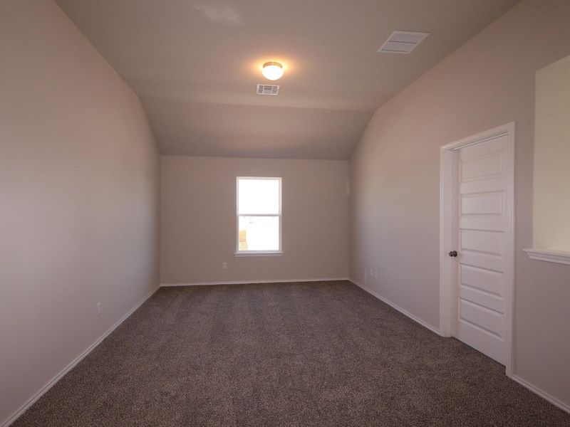 Unfurnished room featuring dark colored carpet and lofted ceiling