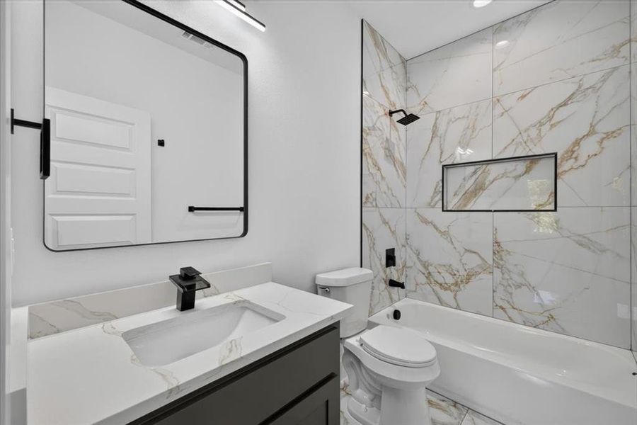 Bathroom featuring a single vanity with a white countertop and rectangular sink, matte black faucet, and a large framed mirror Bathroom featuring a single vanity with a white countertop and rectangular sink, matte black faucet, and a large framed mirror