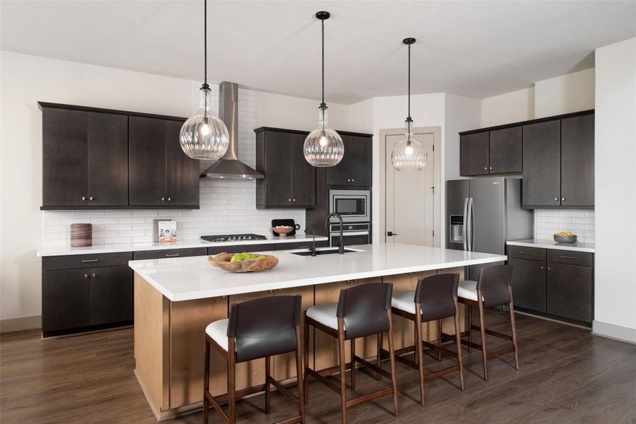 This light and bright kitchen features a large quartz island, white cabinets, a large sink overlooking your family room, recessed lighting, and beautiful backsplash.