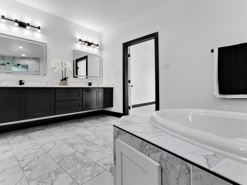 Bathroom featuring a dual vanity with dark cabinetry, white countertops, and dual mirrors