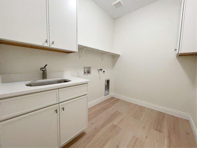 Dedicated laundry room with a sink and extra storage cabinets!