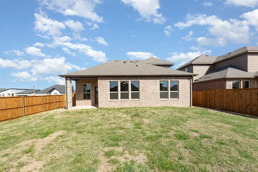 Rear view of property featuring a fenced backyard, a lawn, and brick siding