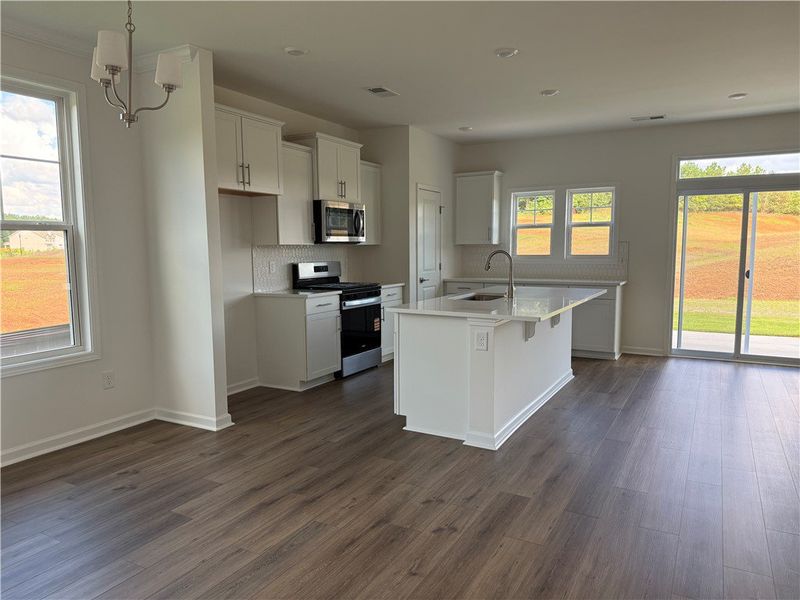 A well-lit kitchen with sleek appliances and an is A well-lit kitchen with sleek appliances and an is