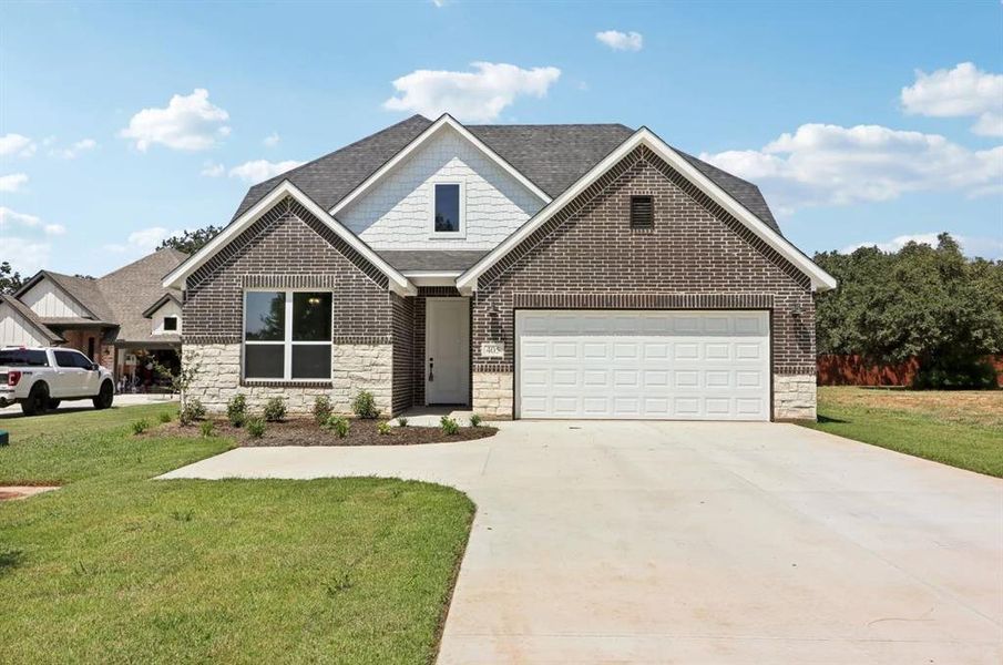 View of front facade featuring a garage and a front lawn