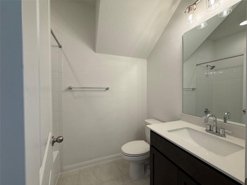 Full bath featuring vanity, a shower, and a textured wall Full bath featuring vanity, a shower, and a textured wall