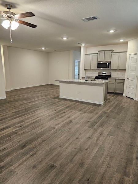 Kitchen featuring gray cabinetry, dark hardwood / wood-style flooring, and a center island with sink