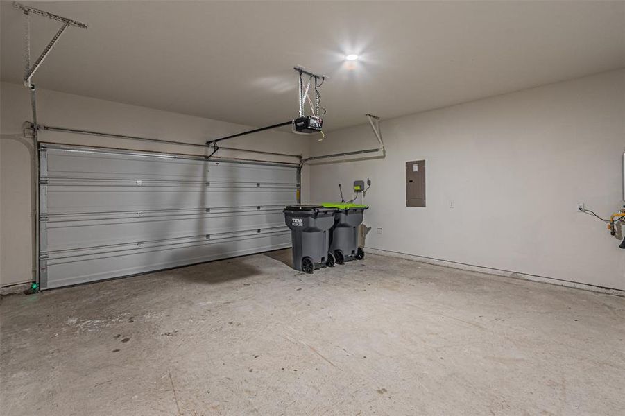 Garage featuring a garage door opener and electric panel