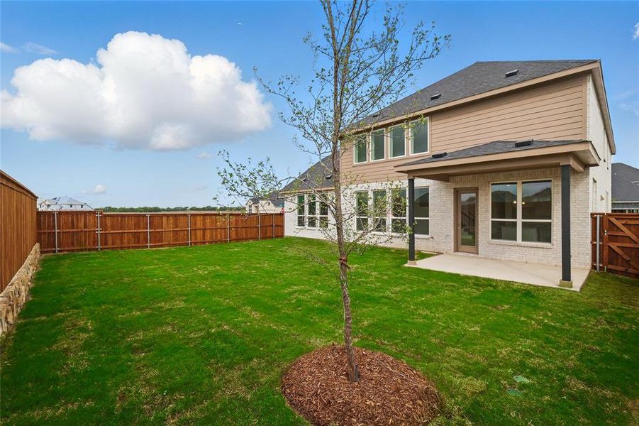 Rear view of house with a fenced backyard, a patio, a yard, and brick siding Rear view of house with a fenced backyard, a patio, a yard, and brick siding
