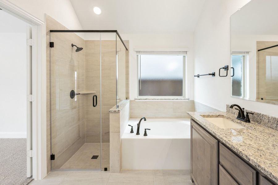 Master bathroom with glass walk-in shower, soaking tub, and granite double vanity with dark fixtures Master bathroom with glass walk-in shower, soaking tub, and granite double vanity with dark fixtures