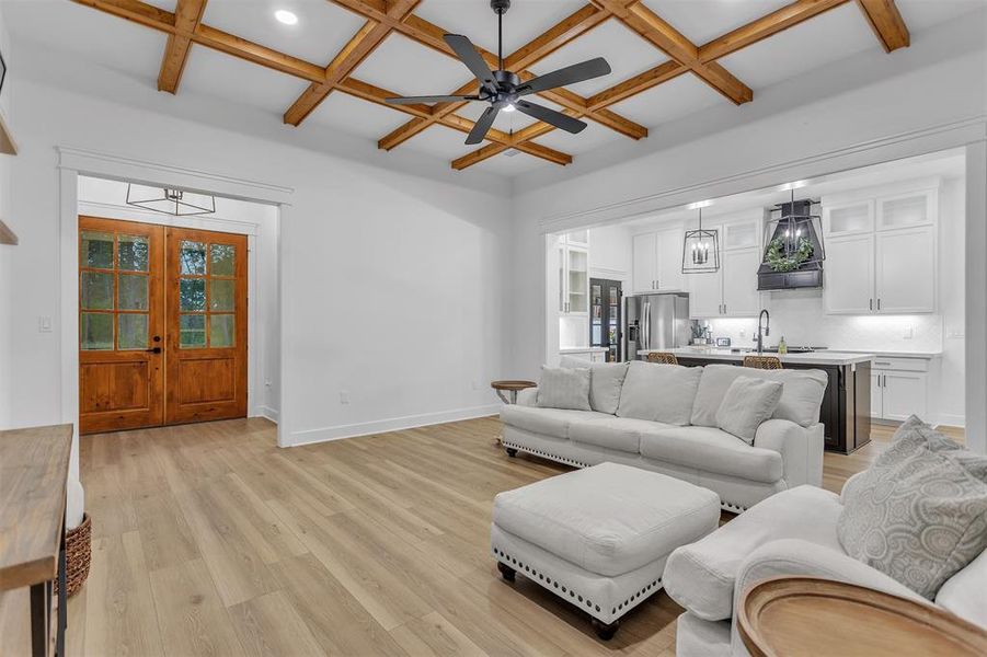 Open living area featuring coffered ceiling, light wood-type flooring and wood accented beam ceiling. Open living area featuring coffered ceiling, light wood-type flooring and wood accented beam ceiling.