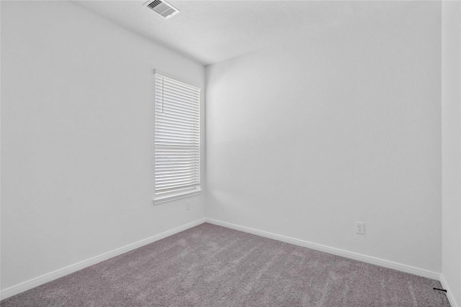 Tucked peacefully in the front of the home, this secondary bedroom offers comfort and style with plush carpeting, neutral paint tones, recessed lighting, a large window with blinds, and a generously sized closet Tucked peacefully in the front of the home, this secondary bedroom offers comfort and style with plush carpeting, neutral paint tones, recessed lighting, a large window with blinds, and a generously sized closet