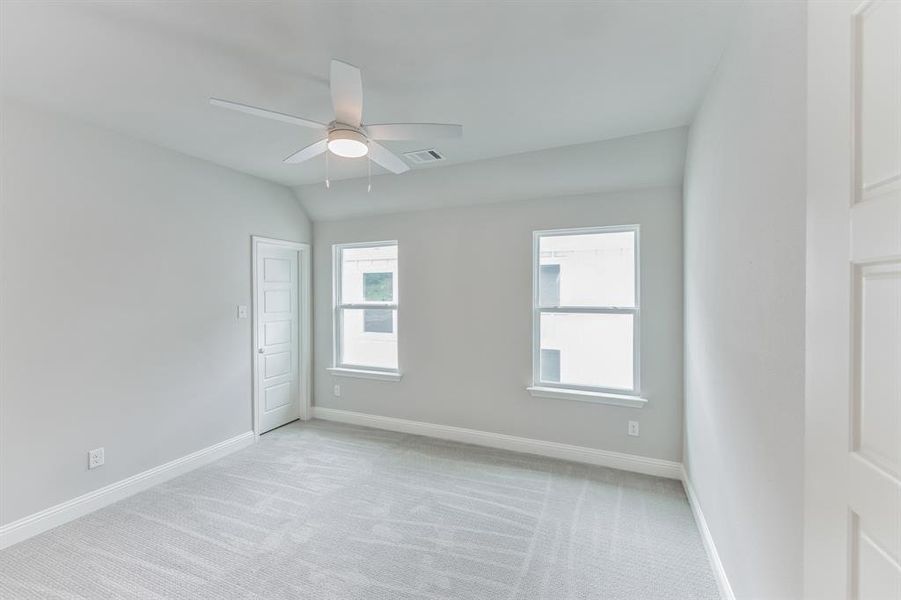 Carpeted empty room featuring lofted ceiling and ceiling fan