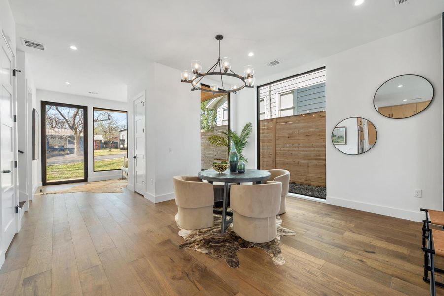 Dining area featuring an inviting chandelier, light wood-style floors, visible vents, and a healthy amount of sunlight