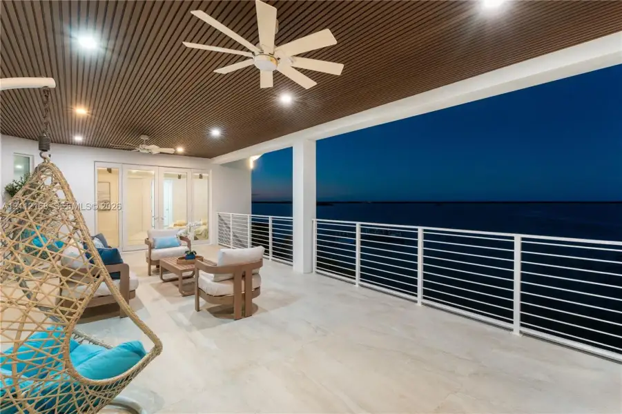 Covered terrace featuring a slatted wood-finish ceiling, large-format tile flooring, white metal horizontal railing, and recessed lighting Covered terrace featuring a slatted wood-finish ceiling, large-format tile flooring, white metal horizontal railing, and recessed lighting