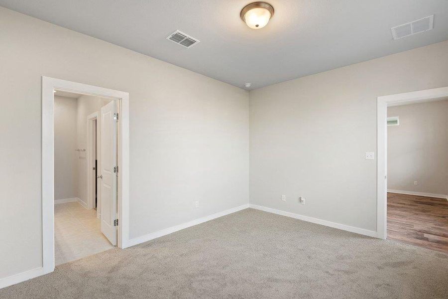 Empty room with light colored carpet and baseboards