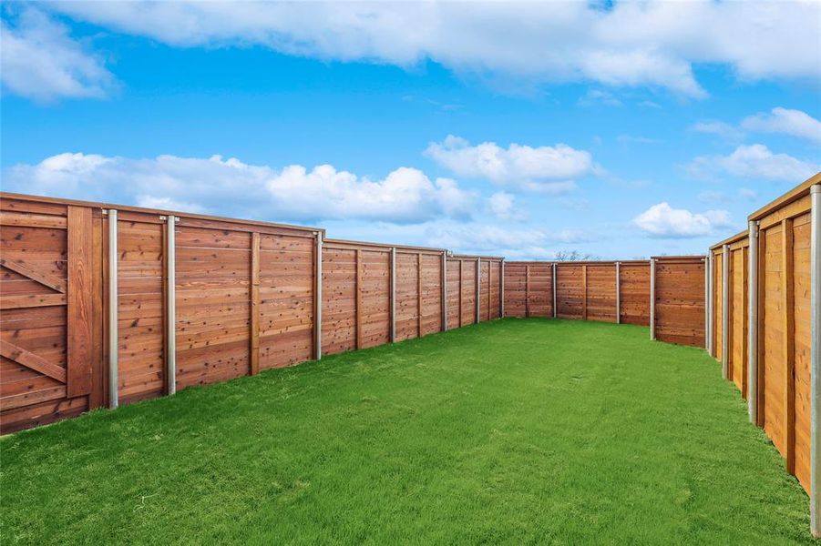 Private backyard featuring a well-maintained lawn and horizontal plank wood fencing with metal posts