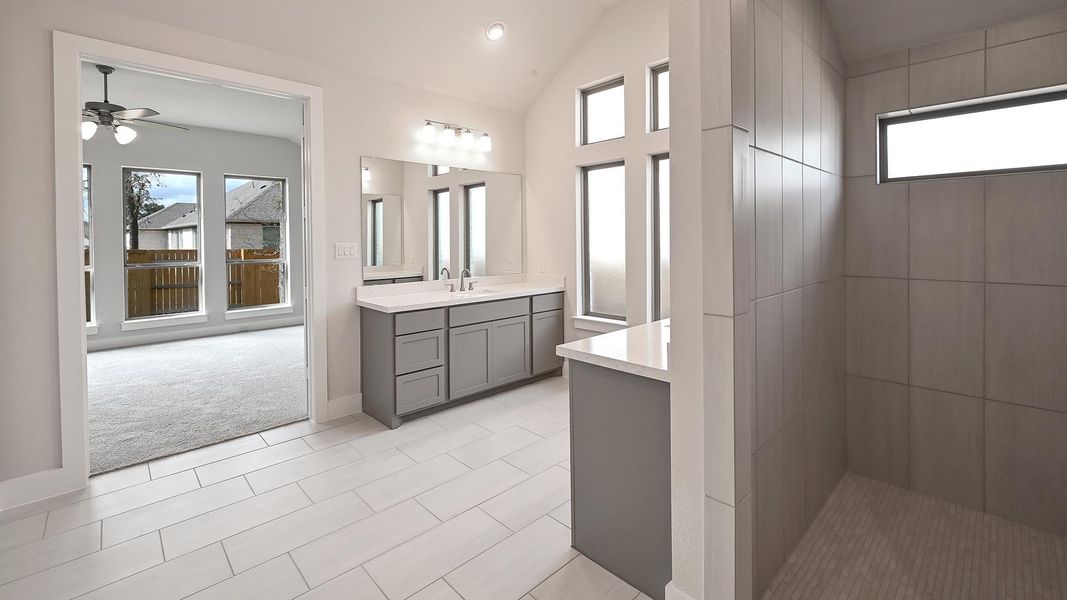 Full bath with vanity, light tile patterned flooring, recessed lighting, vaulted ceiling, and light carpet Full bath with vanity, light tile patterned flooring, recessed lighting, vaulted ceiling, and light carpet