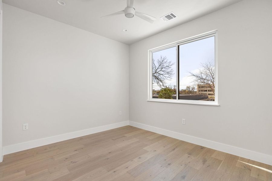 Unfurnished room featuring visible vents, light wood-style flooring, baseboards, and ceiling fan