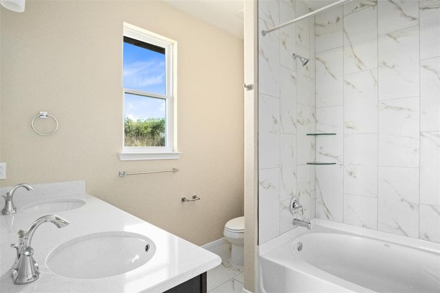 Primary ensuite bathroom featuring double vanity and soaking tub Primary ensuite bathroom featuring double vanity and soaking tub