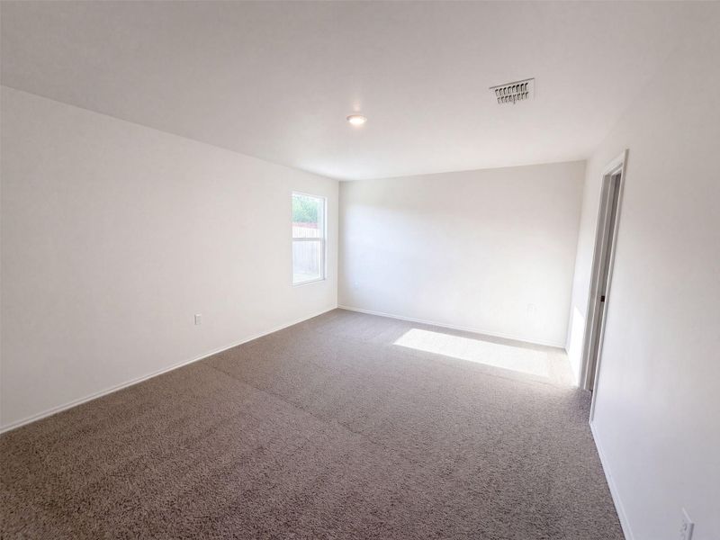 Soft carpeting underfoot and clean plaster walls define this serene bedroom space.