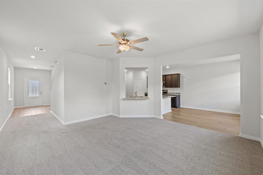 Unfurnished living room featuring ceiling fan, sink, and light wood-type flooring