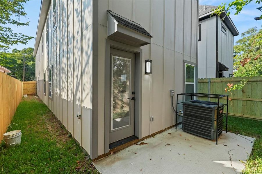 View of exterior entry with board and batten siding and a patio