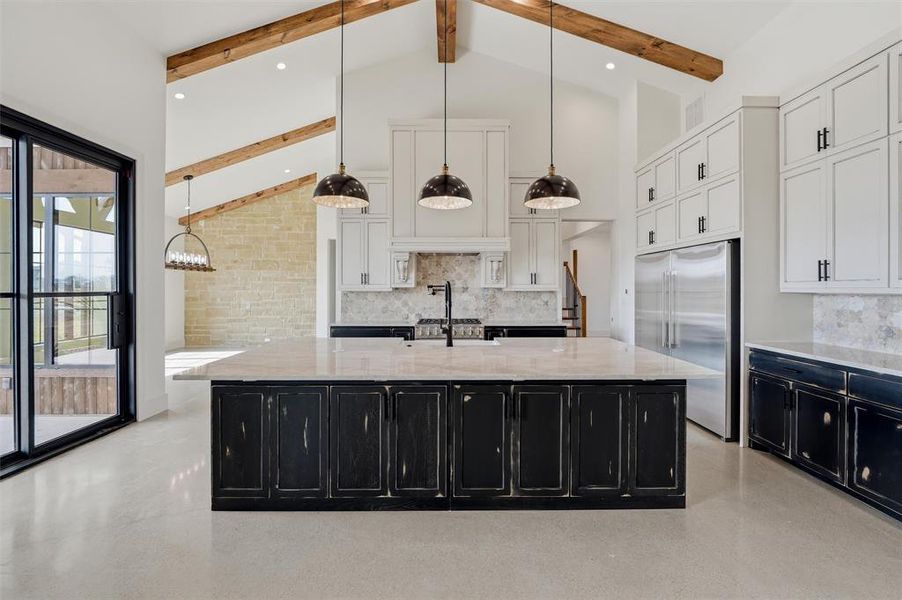 Kitchen with decorative light fixtures, light stone countertops, built in refrigerator, two tone color scheme, and a spacious island Kitchen with decorative light fixtures, light stone countertops, built in refrigerator, two tone color scheme, and a spacious island