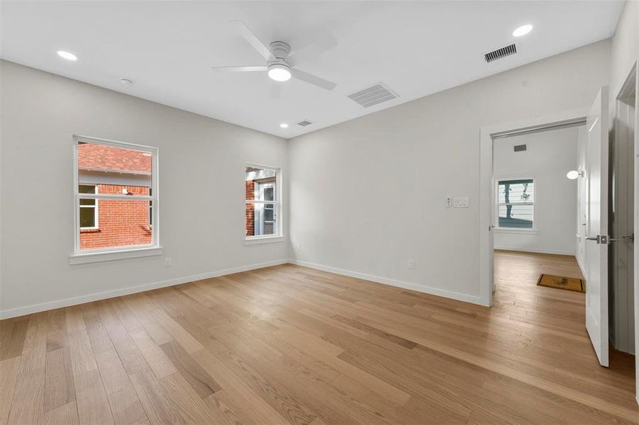 Spare room with ceiling fan, light wood-type flooring, and a healthy amount of sunlight