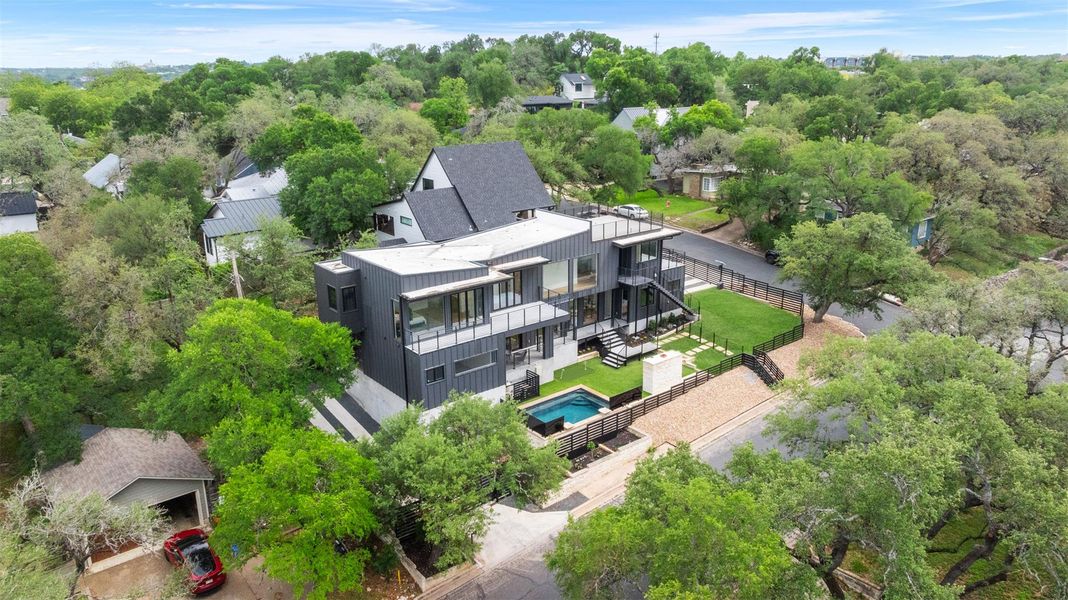 Contemporary property featuring a dark-toned exterior, a swimming pool, and a fenced yard with a lawn