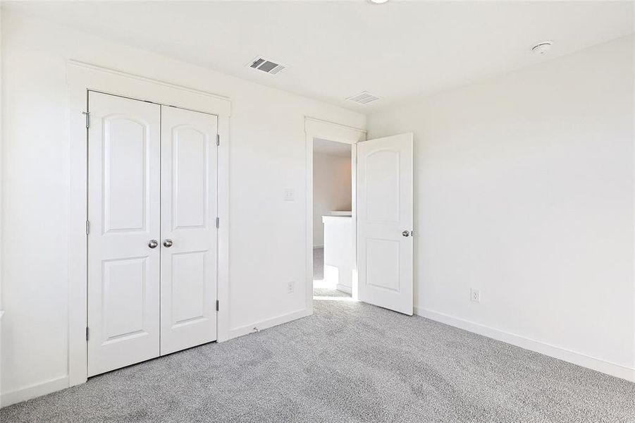 Unfurnished bedroom with light colored carpet and a closet