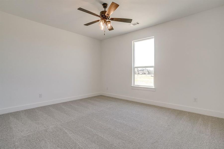 Empty room with light colored carpet and a ceiling fan Empty room with light colored carpet and a ceiling fan