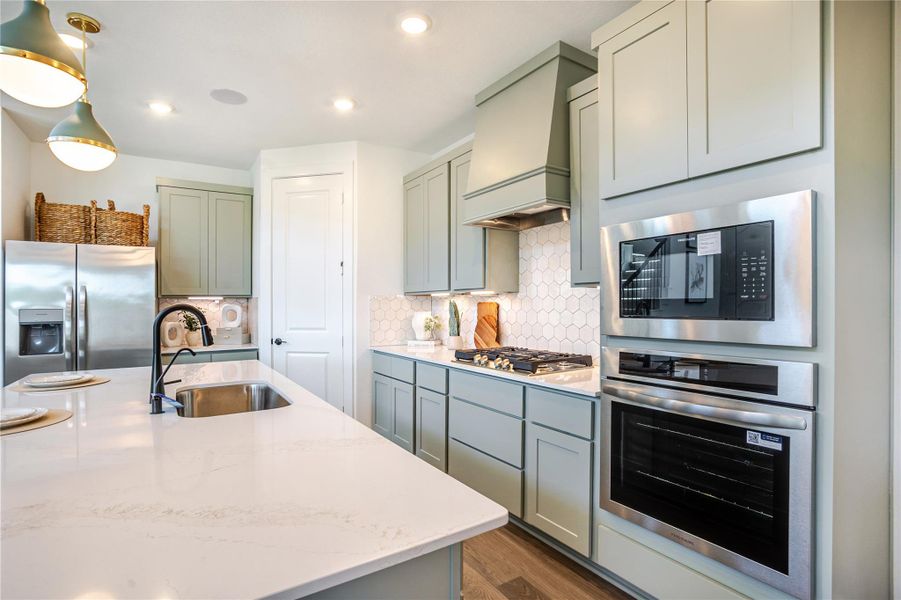 This modern kitchen features sleek stainless steel appliances, a gas cooktop, and a built-in oven. It has elegant cabinetry, a central island with a sink, and stylish pendant lighting, creating a bright and functional cooking space. This modern kitchen features sleek stainless steel appliances, a gas cooktop, and a built-in oven. It has elegant cabinetry, a central island with a sink, and stylish pendant lighting, creating a bright and functional cooking space.