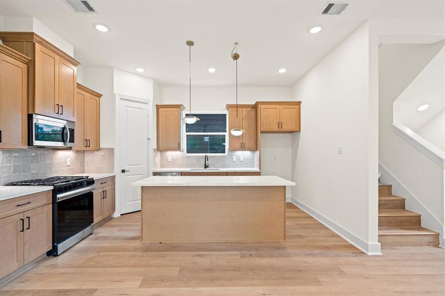 Kitchen features quartz countertops, Zellige mosaic backsplash and stainless steel appliances.