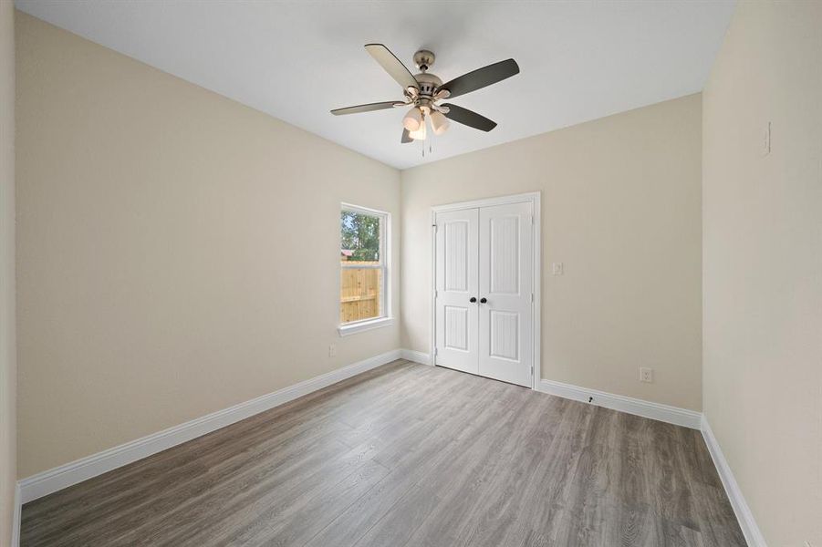 Unfurnished bedroom with ceiling fan, a closet, and wood-type flooring