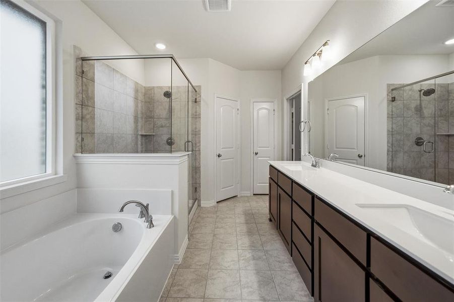 Full bath with double vanity, a bath, a stall shower, and light tile patterned flooring