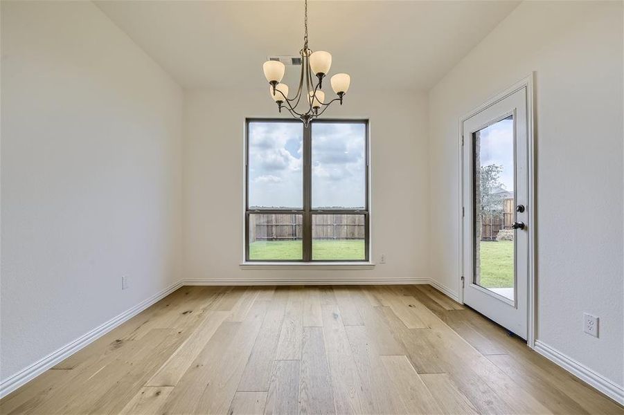 Spare room with a notable chandelier and light wood-type flooring